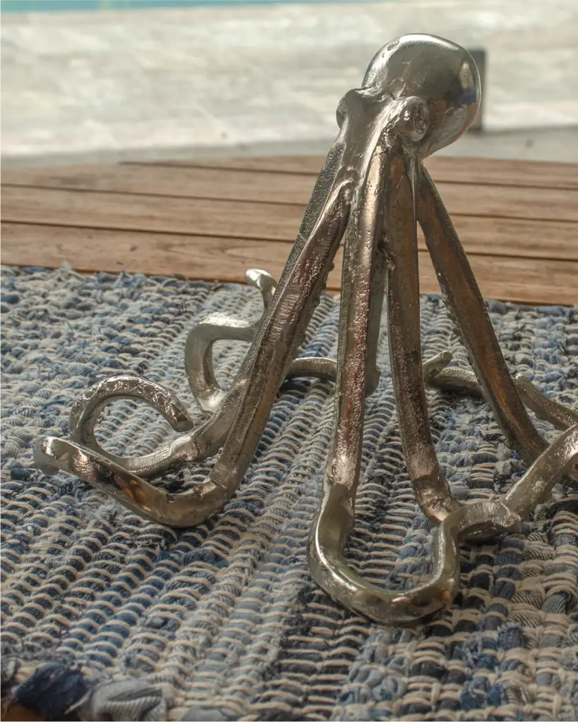 Silver octopus sculpture on woven blue mat.